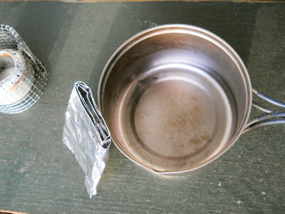 Folded-up windscreen leaning against a cooking pot