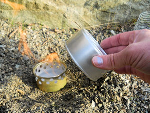 A larger cat food can being dropped over the lit stove to snuff out the flame