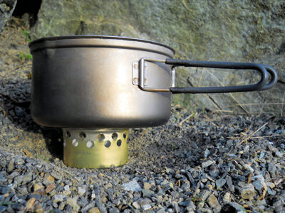 The cat food can stove being used with a pot resting on top of it