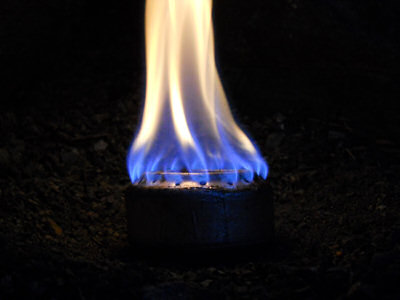 A lit soda can stove burning at night
